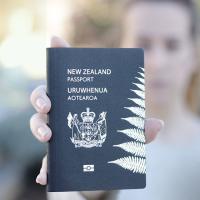 Woman holding a New Zealand passport in her outstretched hand
