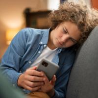 Teen boy peering at a cellphone